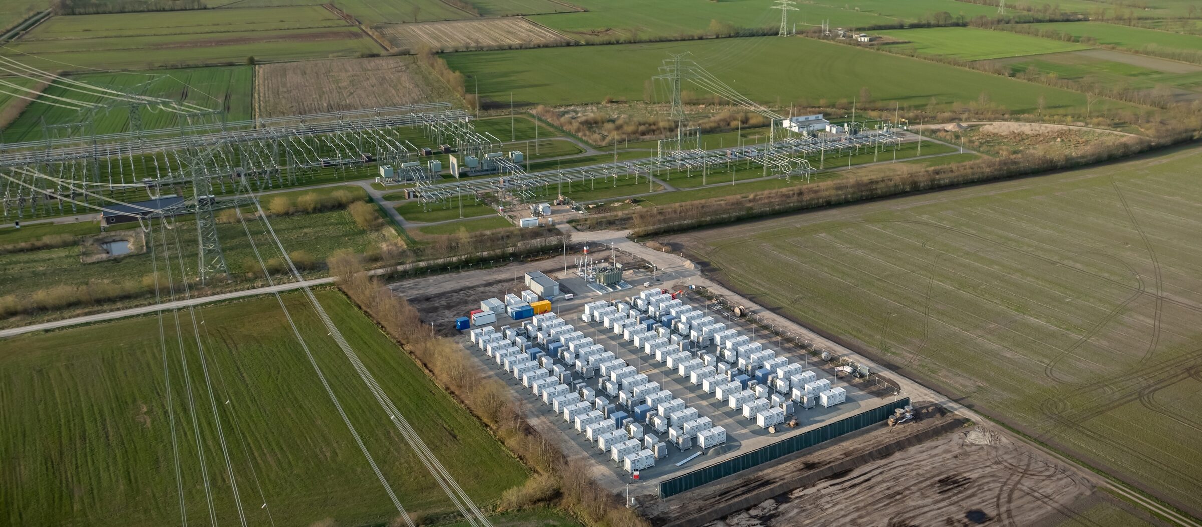Wide aerial of a battery storage facility and substation set in flat farmland
