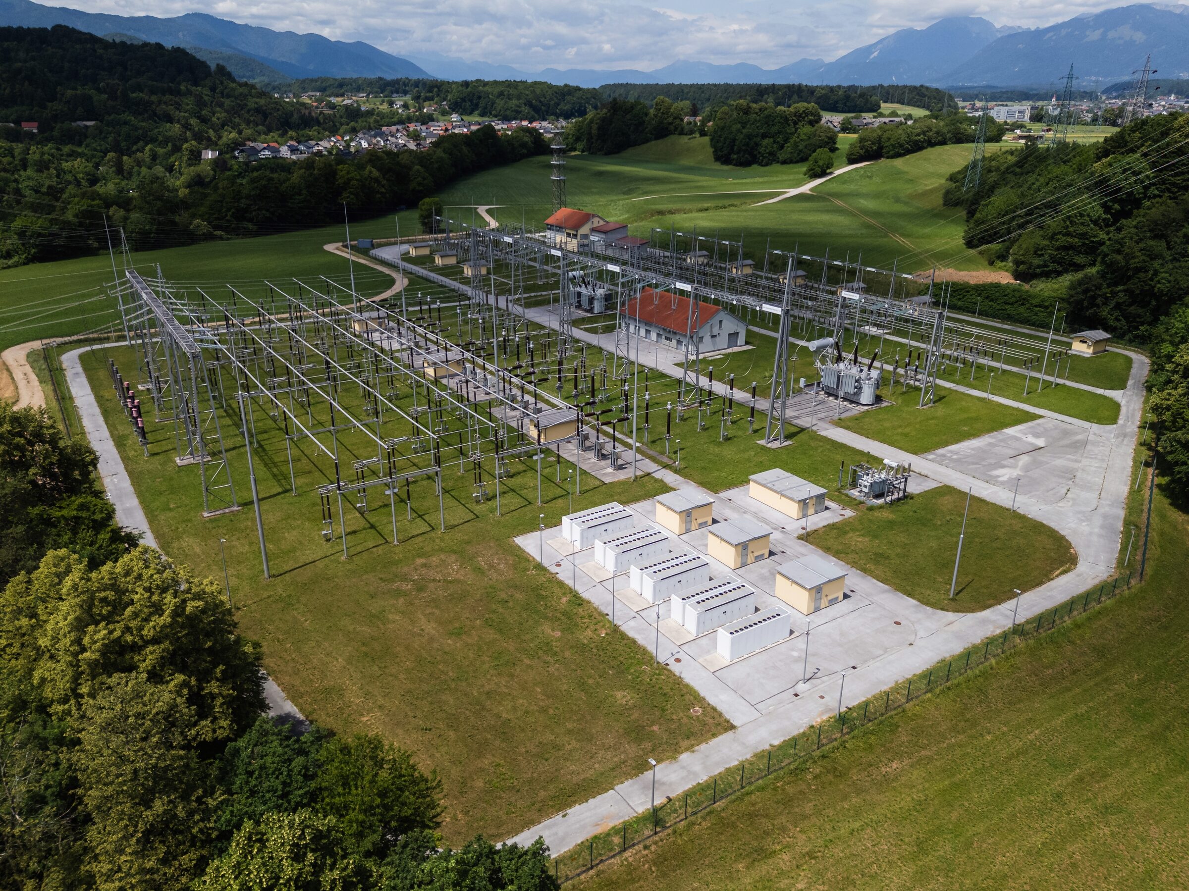 Aerial view of a substation and its battery containers set in rolling green countryside